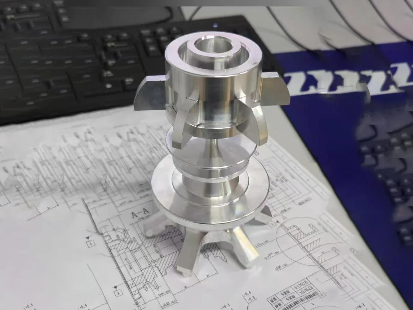 Machined component displayed with an engineering drawing for technical review