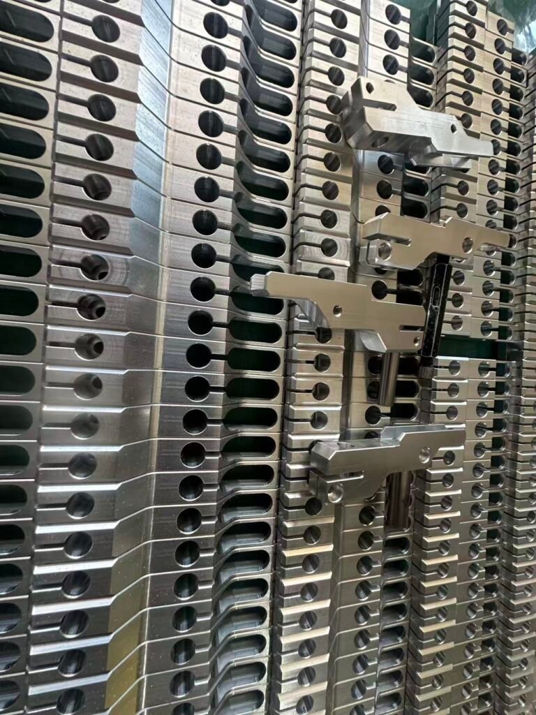 Batch of machined components with circular bores, elongated slots and stepped profiles